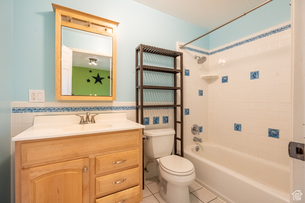 Bathroom with toilet, tile walls, tile patterned flooring, vanity, and shower / bathtub combination