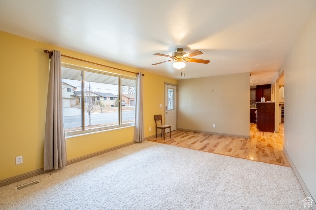 Carpeted spare room featuring ceiling fan and baseboards