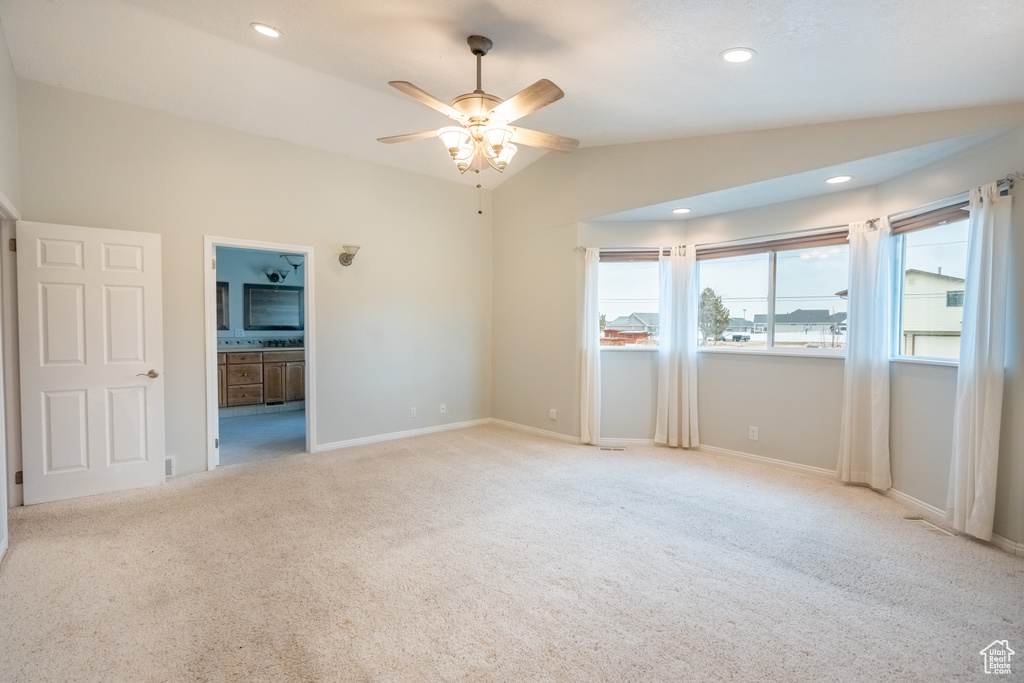 Empty room featuring vaulted ceiling, ceiling fan, light colored carpet, baseboards, and recessed lighting