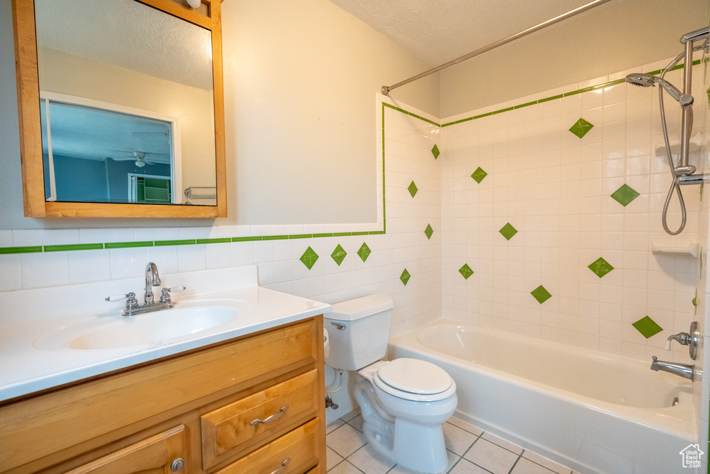 Full bathroom with vanity, toilet, bathtub / shower combination, tile patterned flooring, and tile walls