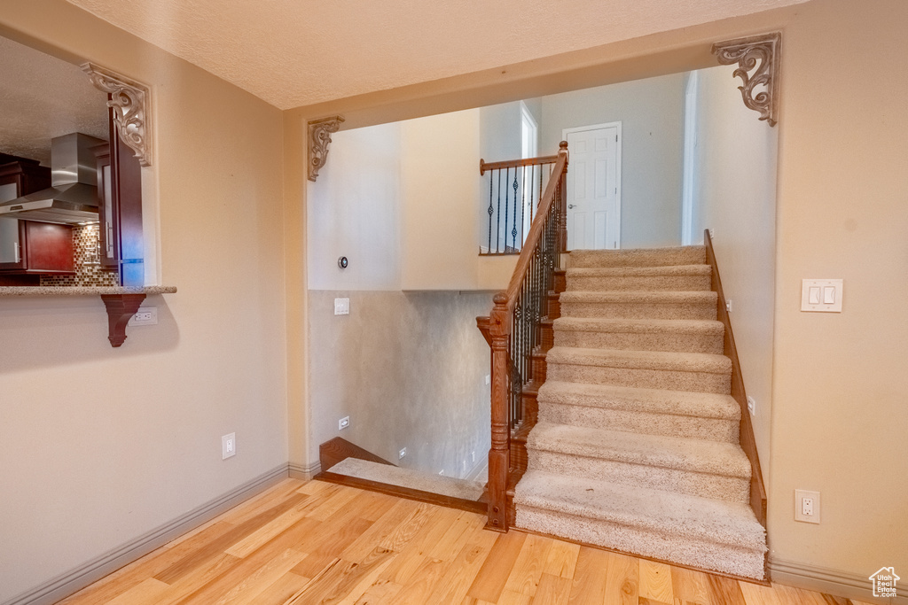 Staircase with wood finished floors and baseboards