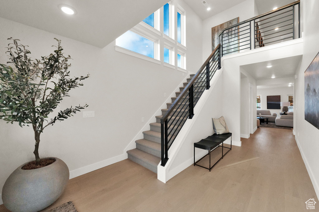 Staircase featuring wood finished floors, baseboards, a towering ceiling, and recessed lighting