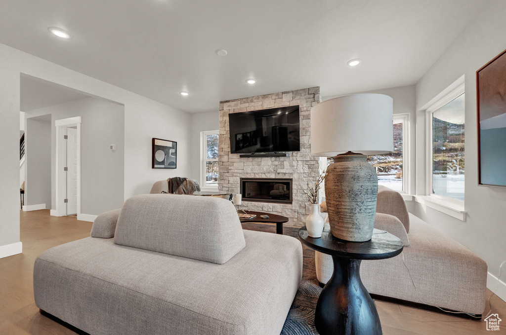 Living area featuring plenty of natural light, baseboards, a stone fireplace, wood finished floors, and recessed lighting
