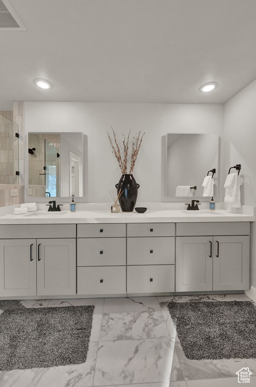 Full bathroom featuring a tile shower, double vanity, marble look tiles, and recessed lighting