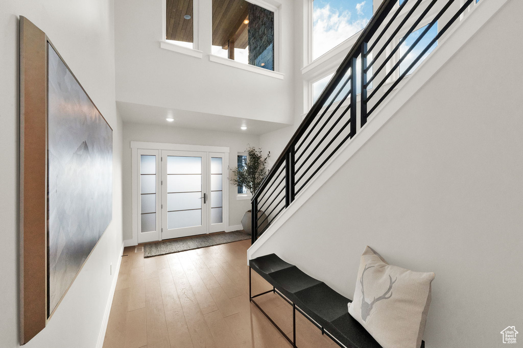 Entryway featuring stairs, healthy amount of natural light, a towering ceiling, hardwood / wood-style floors, and recessed lighting