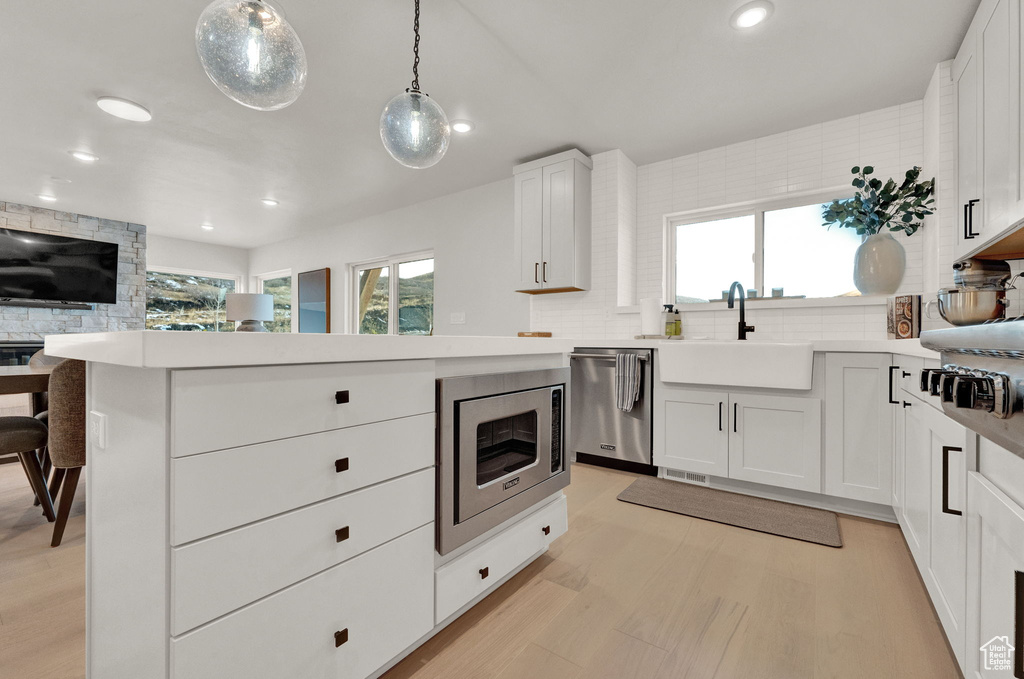 Kitchen featuring appliances with stainless steel finishes, a sink, recessed lighting, light wood-type flooring, and light countertops