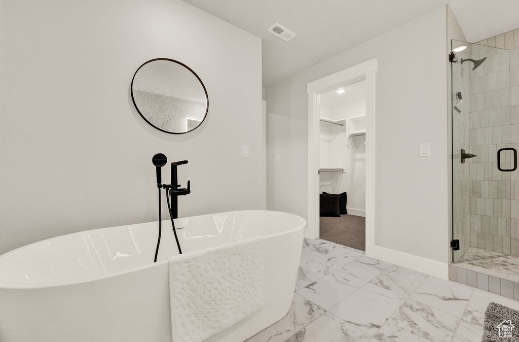 Bathroom with a spacious closet, a shower stall, marble finish floors, a soaking tub, and baseboards