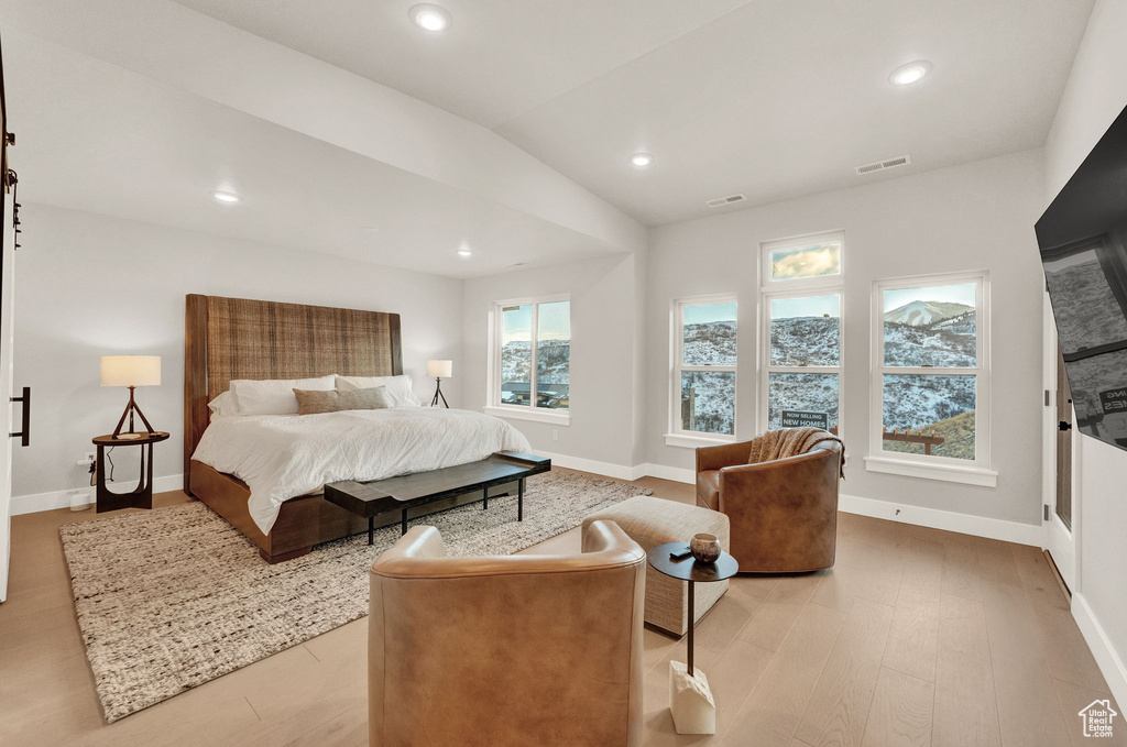 Bedroom with light wood finished floors, baseboards, recessed lighting, and lofted ceiling