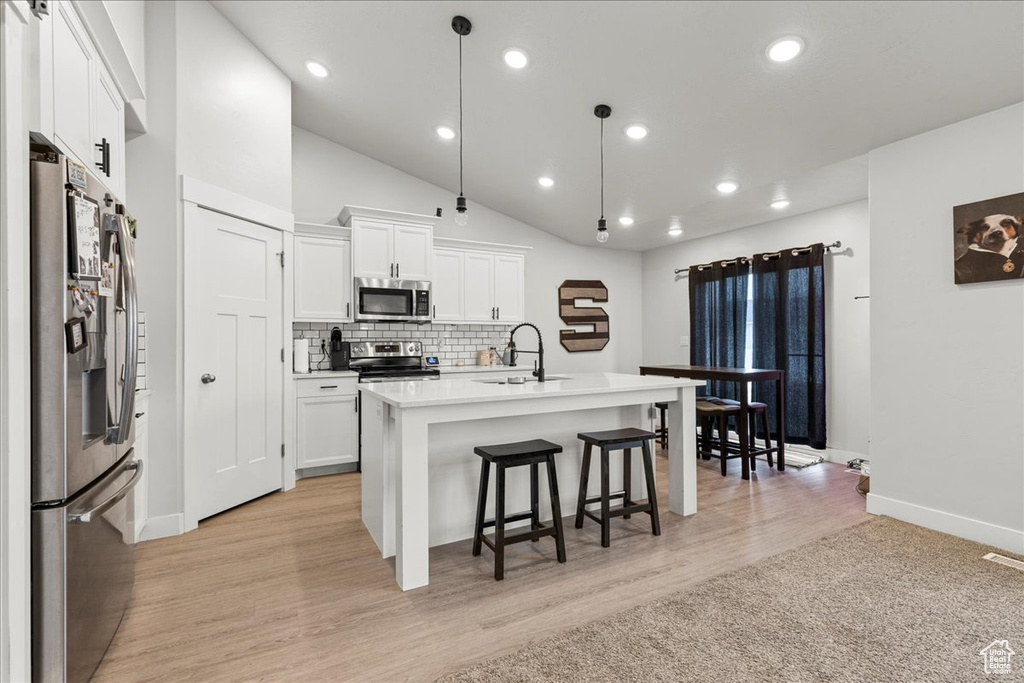 Kitchen featuring appliances with stainless steel finishes, a sink, baseboards, a kitchen breakfast bar, and white cabinetry