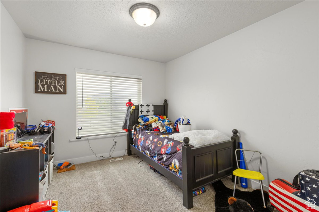Bedroom with carpet, baseboards, and a textured ceiling