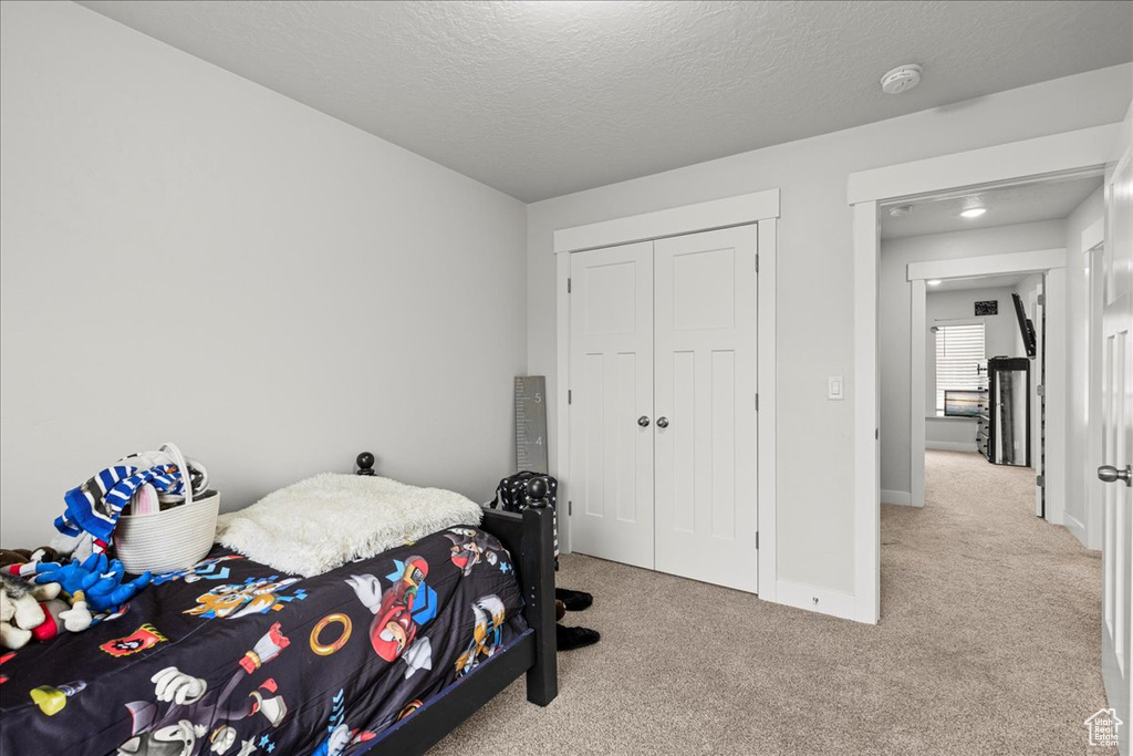 Carpeted bedroom featuring baseboards, a closet, and a textured ceiling