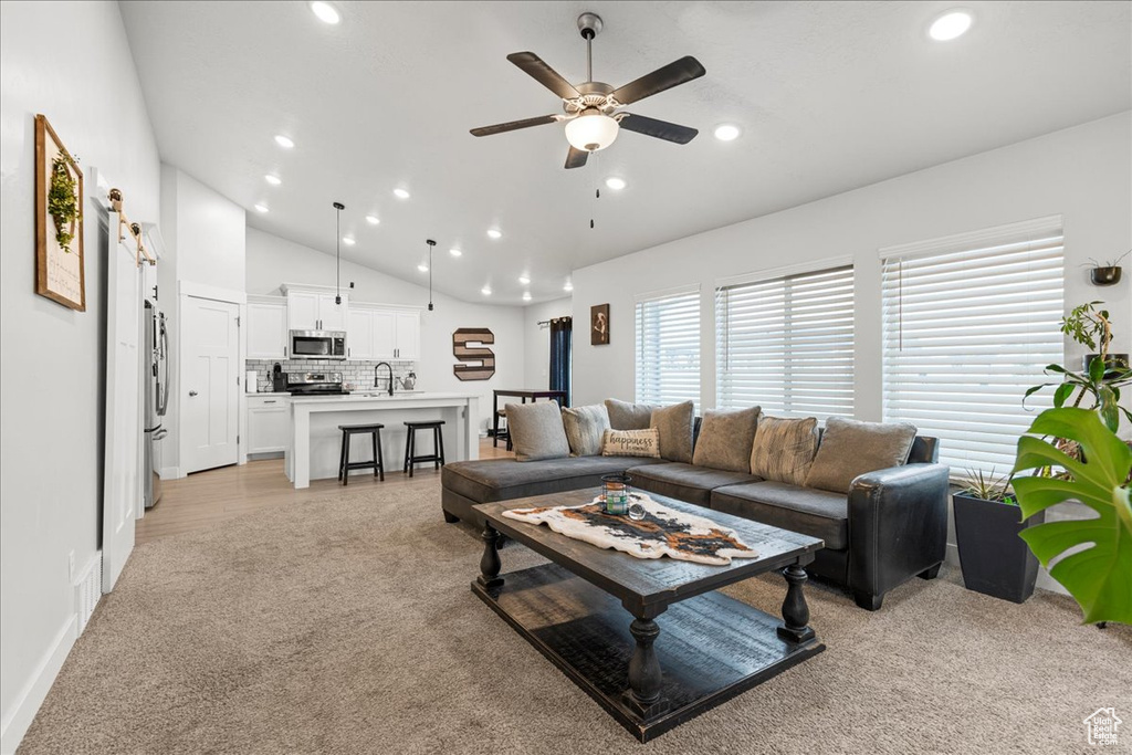 Living room featuring light carpet, vaulted ceiling, ceiling fan, and recessed lighting