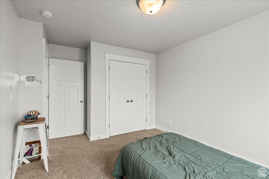 Bedroom with carpet, baseboards, a closet, and a textured ceiling