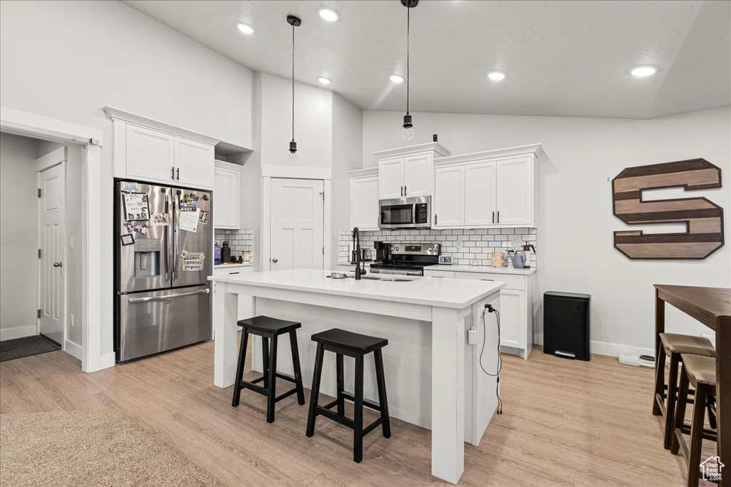 Kitchen with appliances with stainless steel finishes, light countertops, white cabinetry, tasteful backsplash, and recessed lighting