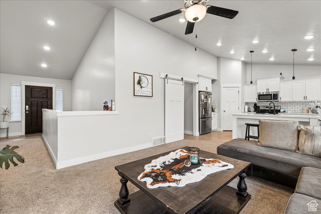 Living room featuring a barn door, high vaulted ceiling, ceiling fan, recessed lighting, and baseboards