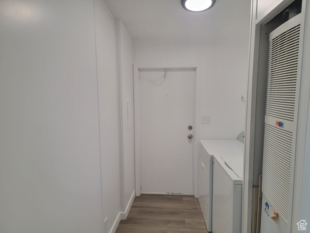 Laundry room featuring a heating unit, washing machine and clothes dryer, and wood finished floors