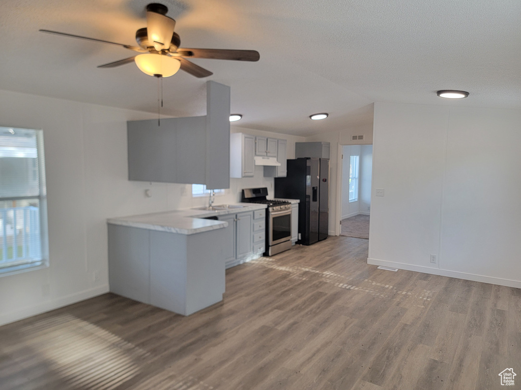 Kitchen featuring appliances with stainless steel finishes, under cabinet range hood, a ceiling fan, light countertops, and light wood-style floors