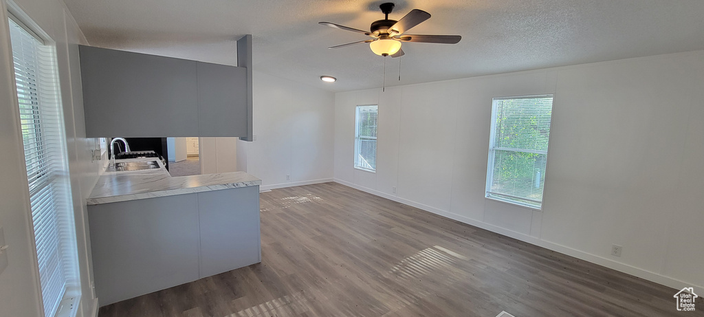 Unfurnished office featuring a sink, wood finished floors, ceiling fan, baseboards, and lofted ceiling