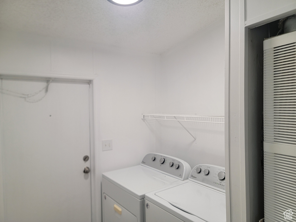 Washroom with washing machine and clothes dryer, a heating unit, and a textured ceiling