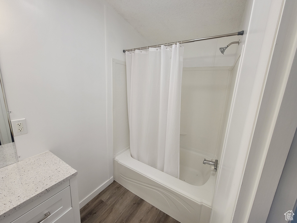 Bathroom featuring wood finished floors, vanity, shower / tub combo with curtain, and baseboards