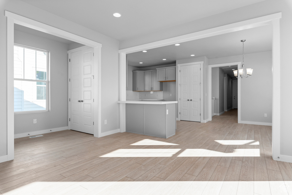 Kitchen featuring light countertops, a chandelier, recessed lighting, a peninsula, and light wood-style floors
