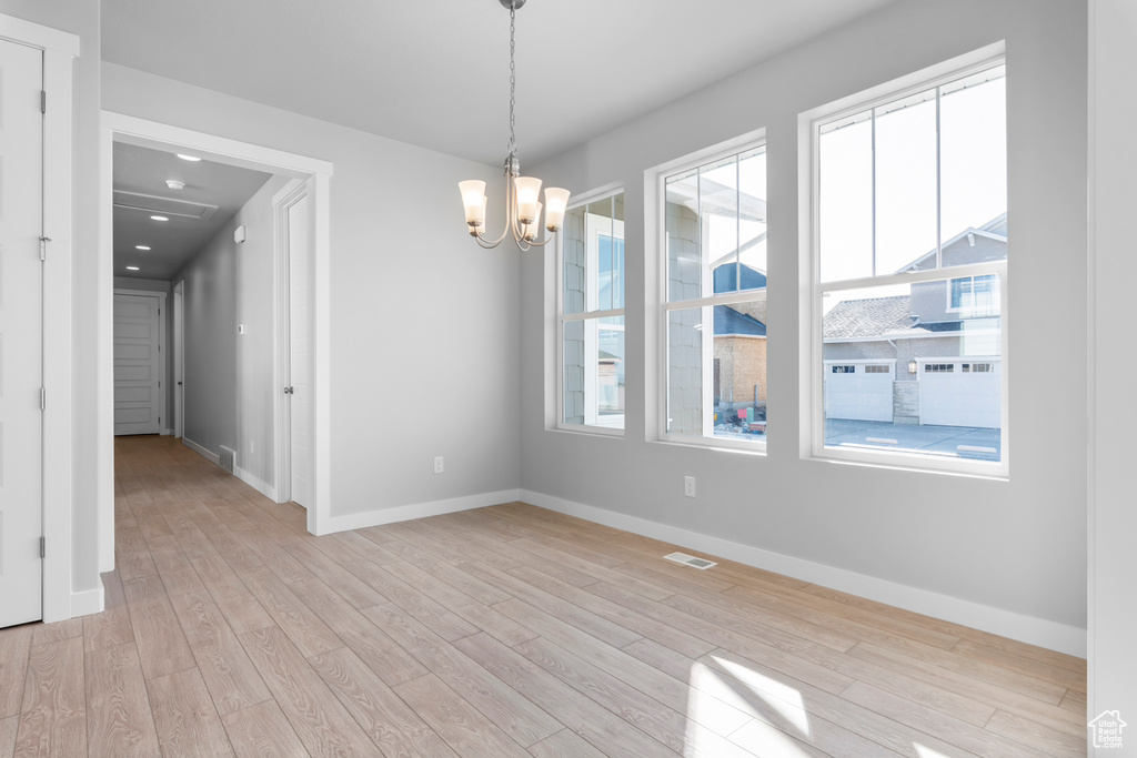 Spare room featuring a chandelier, baseboards, light wood-type flooring, and recessed lighting
