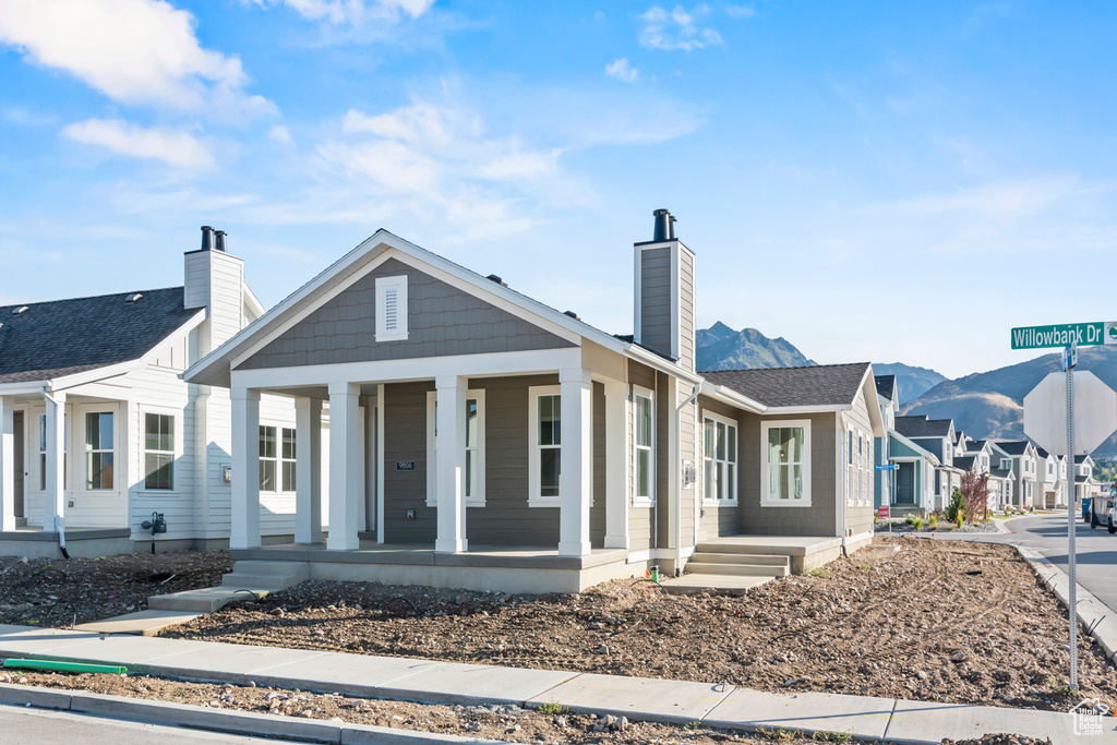 View of front of house featuring covered porch, a chimney, and a residential view