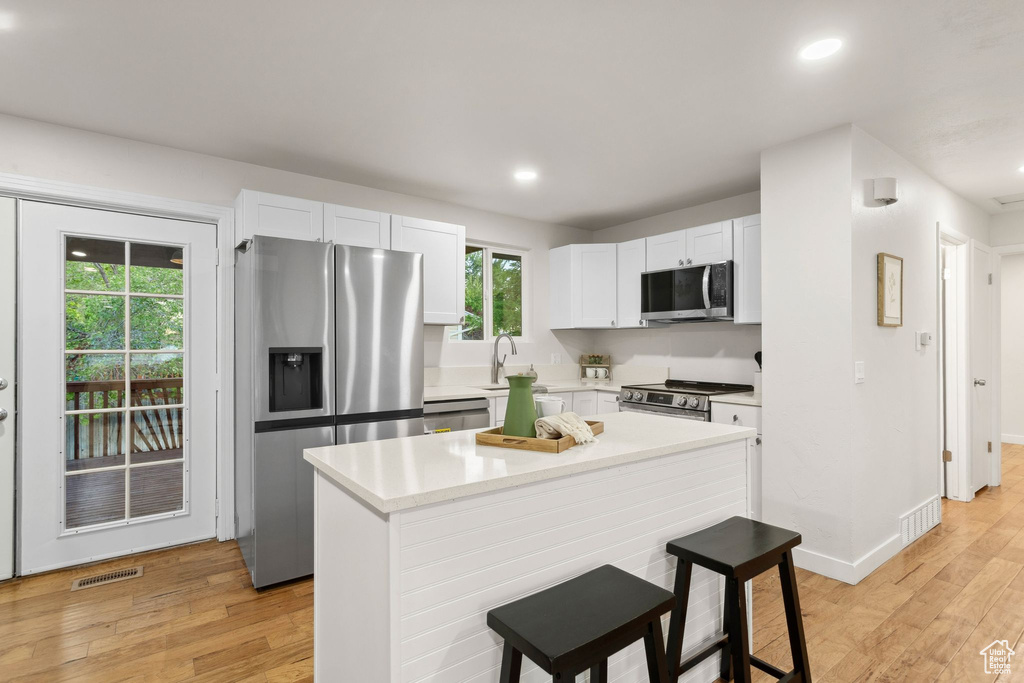 Kitchen featuring appliances with stainless steel finishes, recessed lighting, light wood-type flooring, a center island, and light countertops
