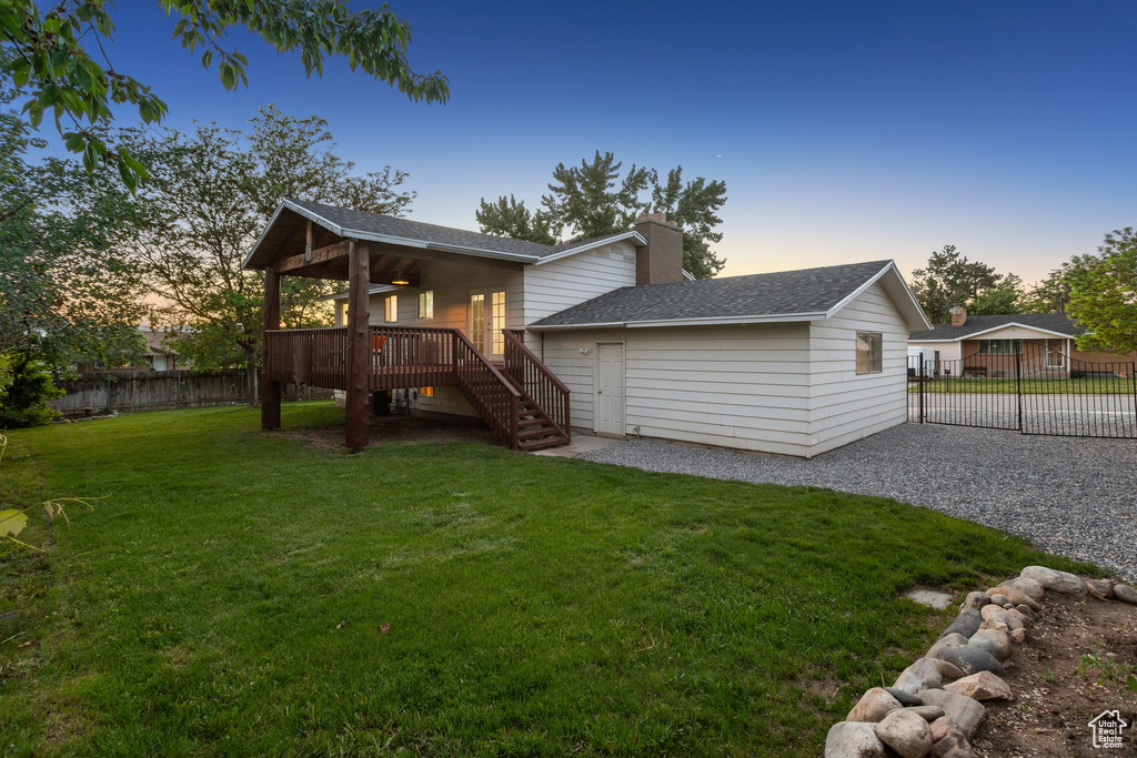 Rear view of house with stairs, a wooden deck, roof with shingles, a chimney, and gravel driveway