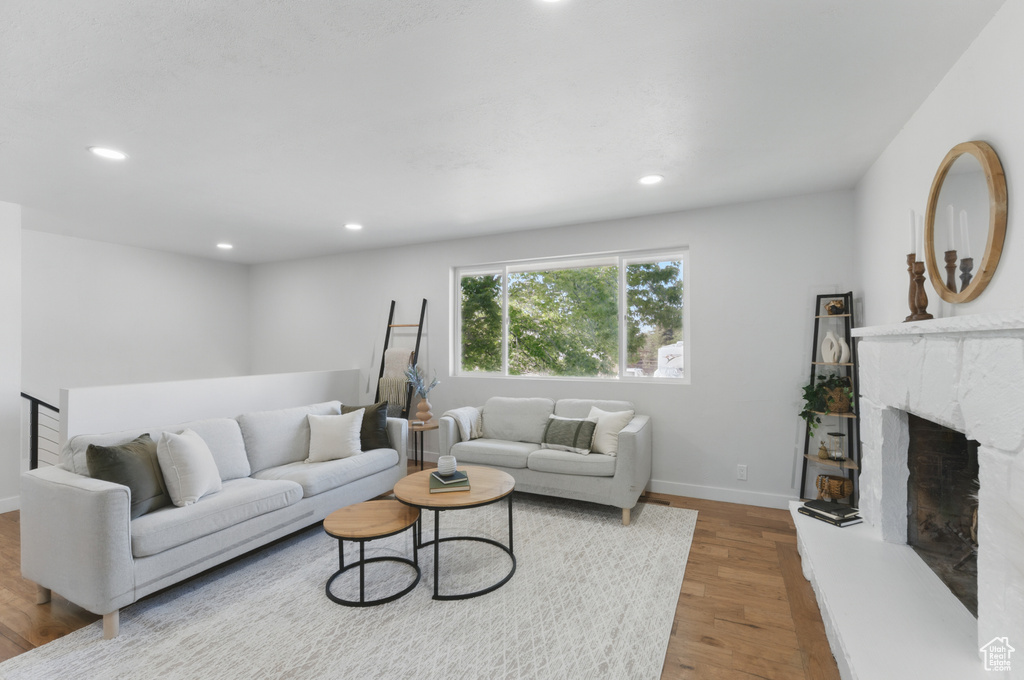 Living area with recessed lighting, wood finished floors, baseboards, and a premium fireplace