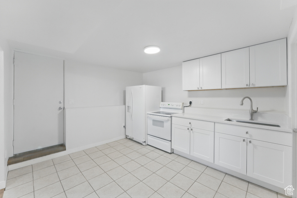 Kitchen featuring white appliances, a sink, light countertops, white cabinetry, and baseboards