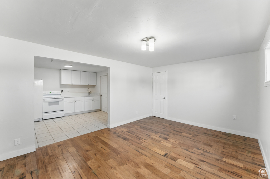 Unfurnished living room featuring light wood-style flooring, baseboards, and a sink