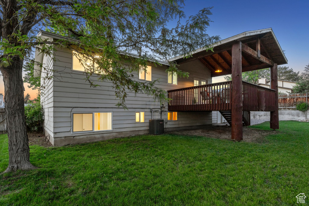 Rear view of property featuring a wooden deck, a yard, and cooling unit