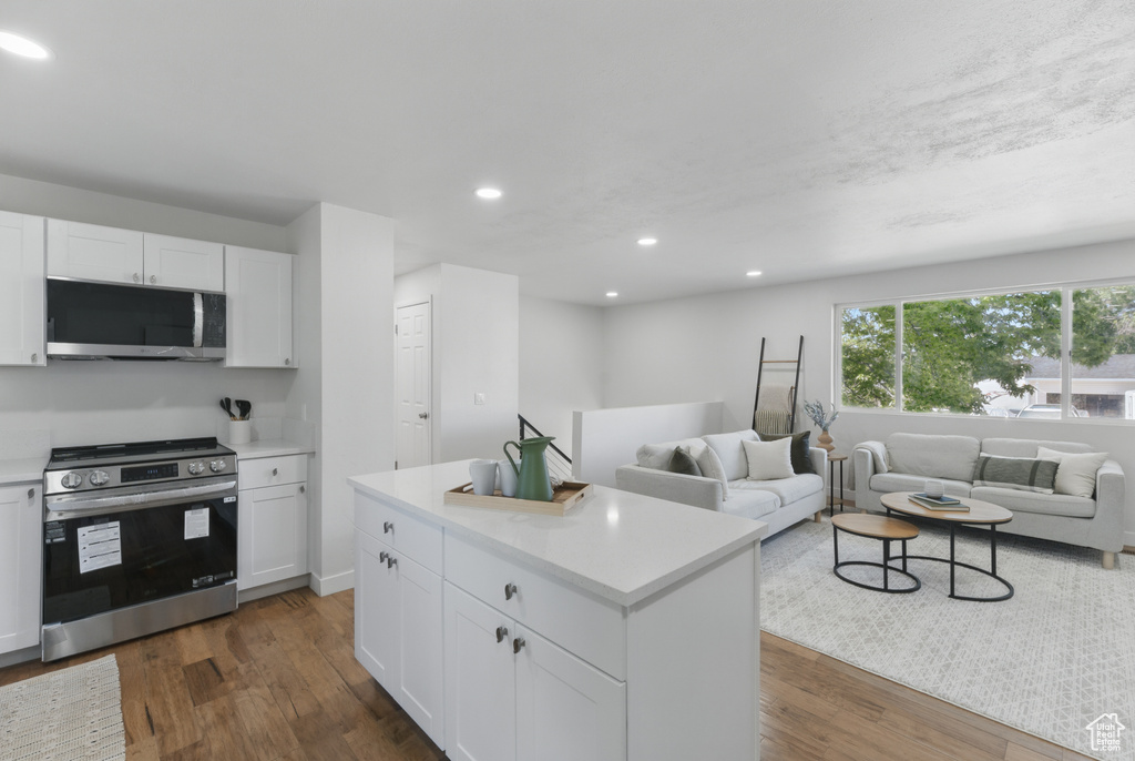 Kitchen with stainless steel appliances, dark wood-style floors, light countertops, recessed lighting, and white cabinets