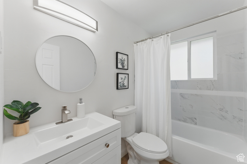 Bathroom featuring toilet, vanity, and shower / bath combo with shower curtain