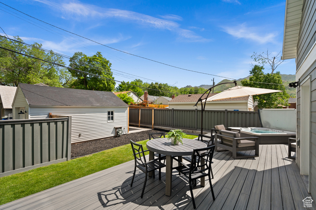 Wooden terrace featuring outdoor dining space, a fenced backyard, and an outdoor hot tub