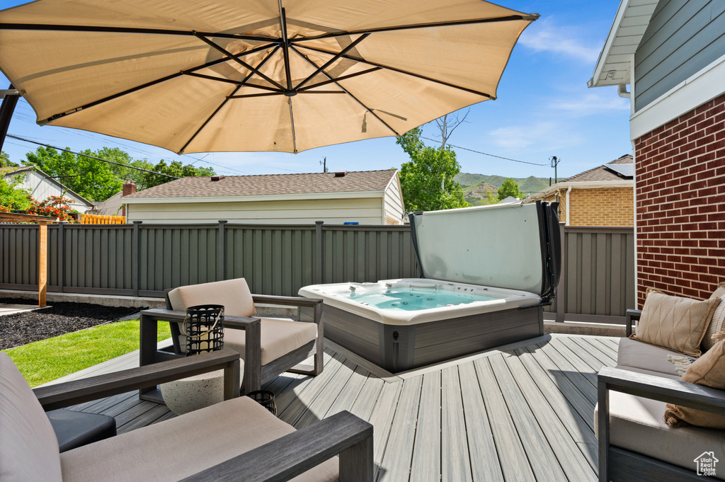 Deck featuring a covered hot tub, a fenced backyard, and an outdoor hangout area