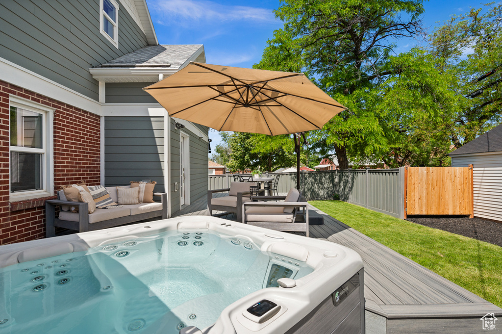 Wooden deck with a hot tub and an outdoor living space