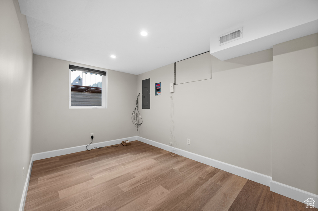 Below grade area with electric panel, light wood-style floors, baseboards, and recessed lighting