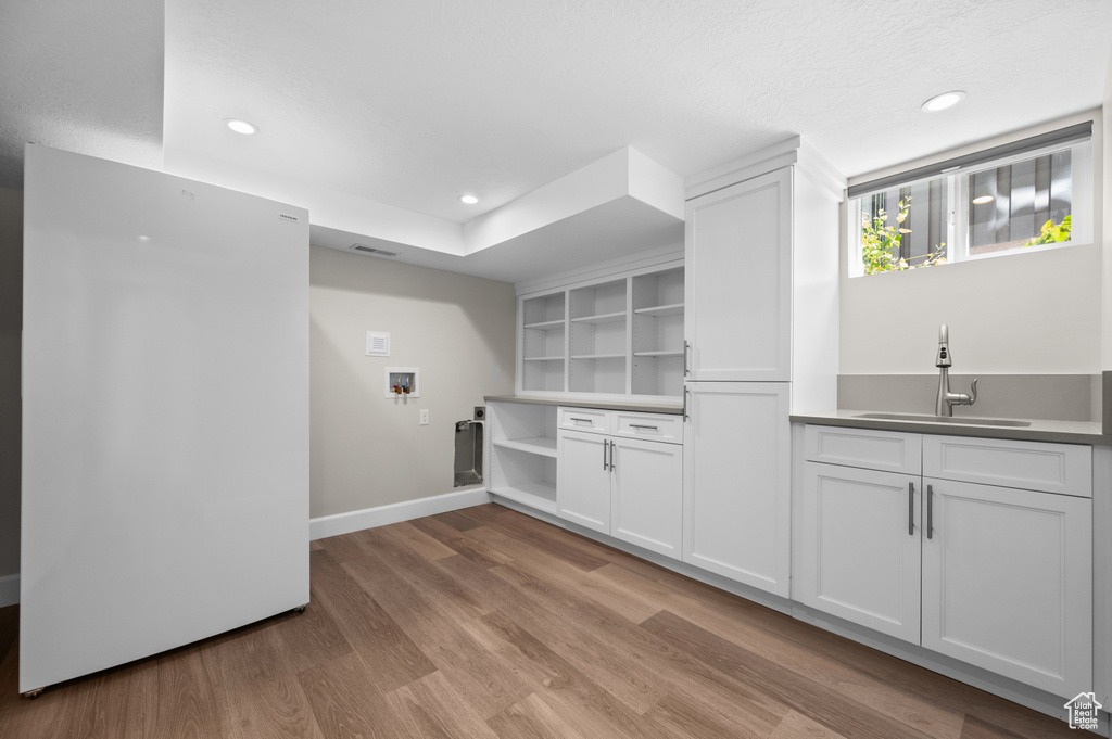 Laundry area featuring light wood-type flooring, recessed lighting, hookup for a washing machine, bar with sink, and baseboards