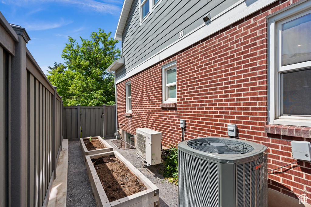 View of side of home with central air condition unit, a garden, and brick siding