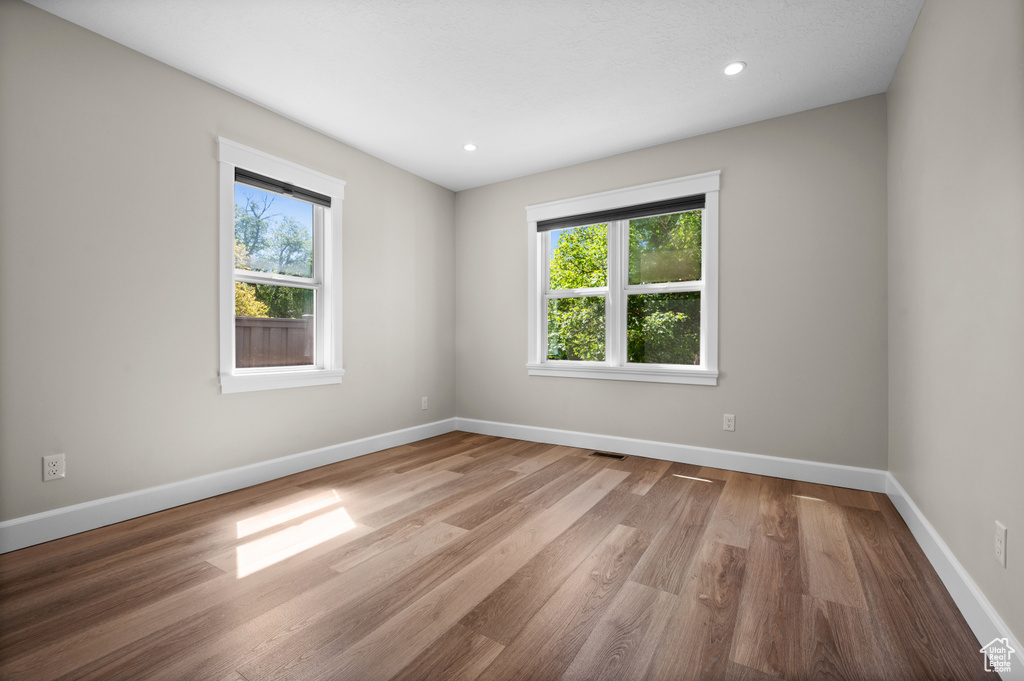 Unfurnished room featuring wood finished floors, baseboards, and recessed lighting