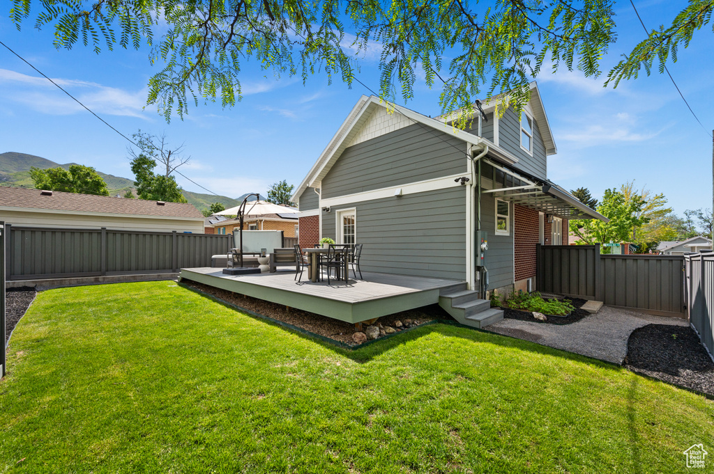 Back of property with a deck with mountain view, outdoor dining area, and a gate