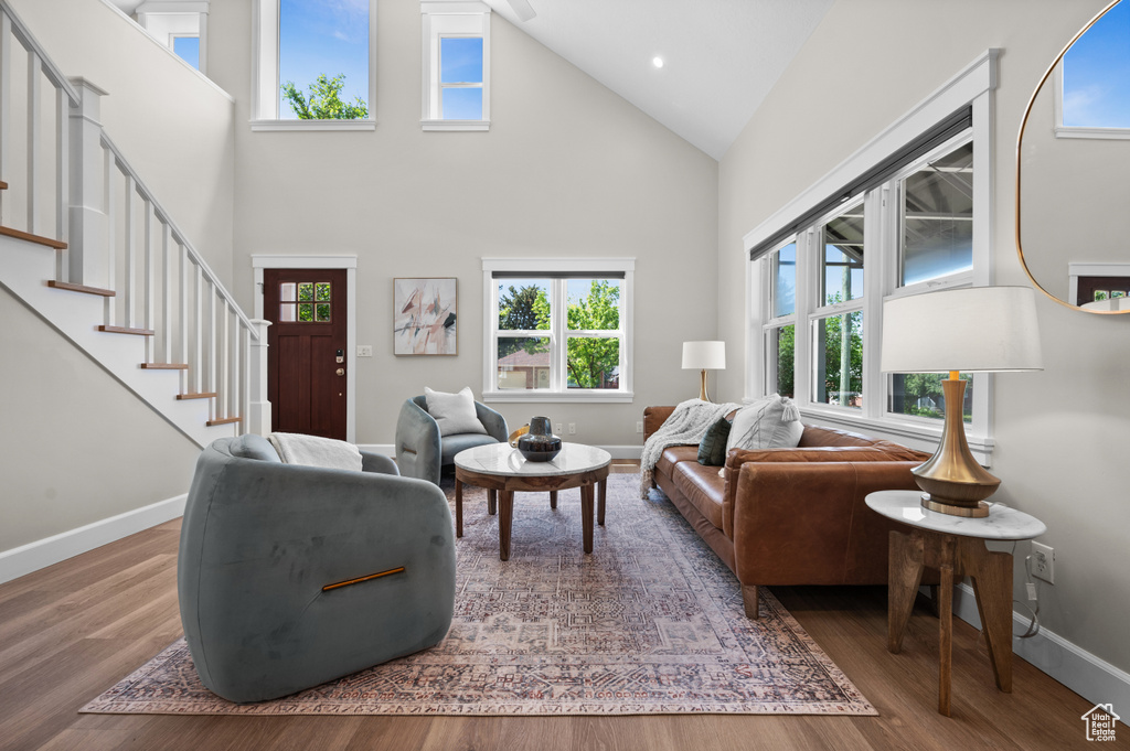 Living room featuring high vaulted ceiling, baseboards, wood finished floors, stairs, and recessed lighting
