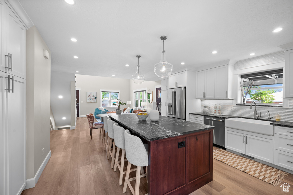 Kitchen featuring a sink, appliances with stainless steel finishes, recessed lighting, light wood finished floors, and a kitchen island