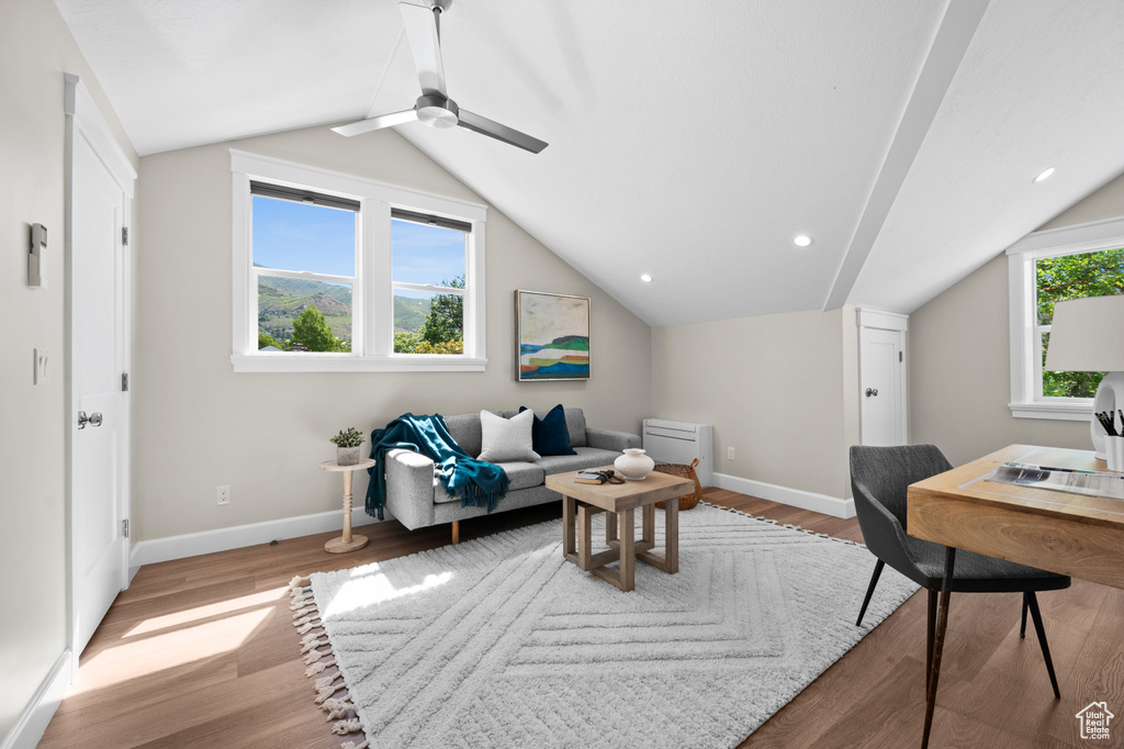 Living area with vaulted ceiling, baseboards, wood finished floors, and ceiling fan