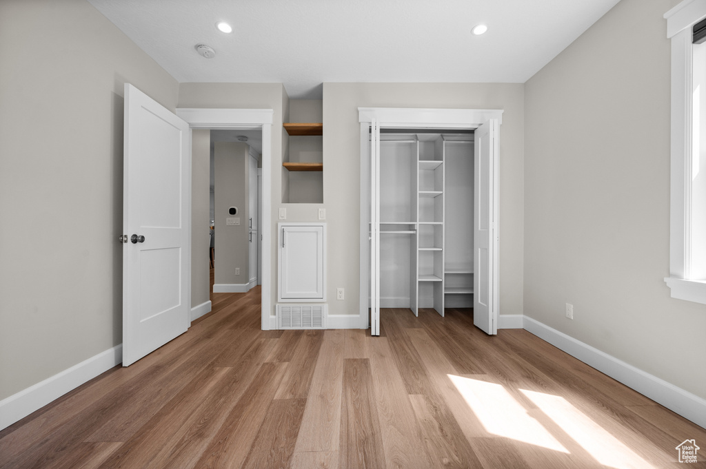 Unfurnished bedroom featuring light wood-style flooring, baseboards, a closet, and recessed lighting