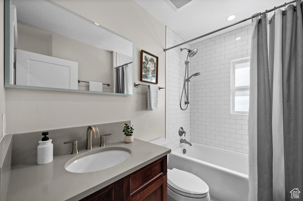 Full bathroom with vanity, shower / bath combination with curtain, and toilet