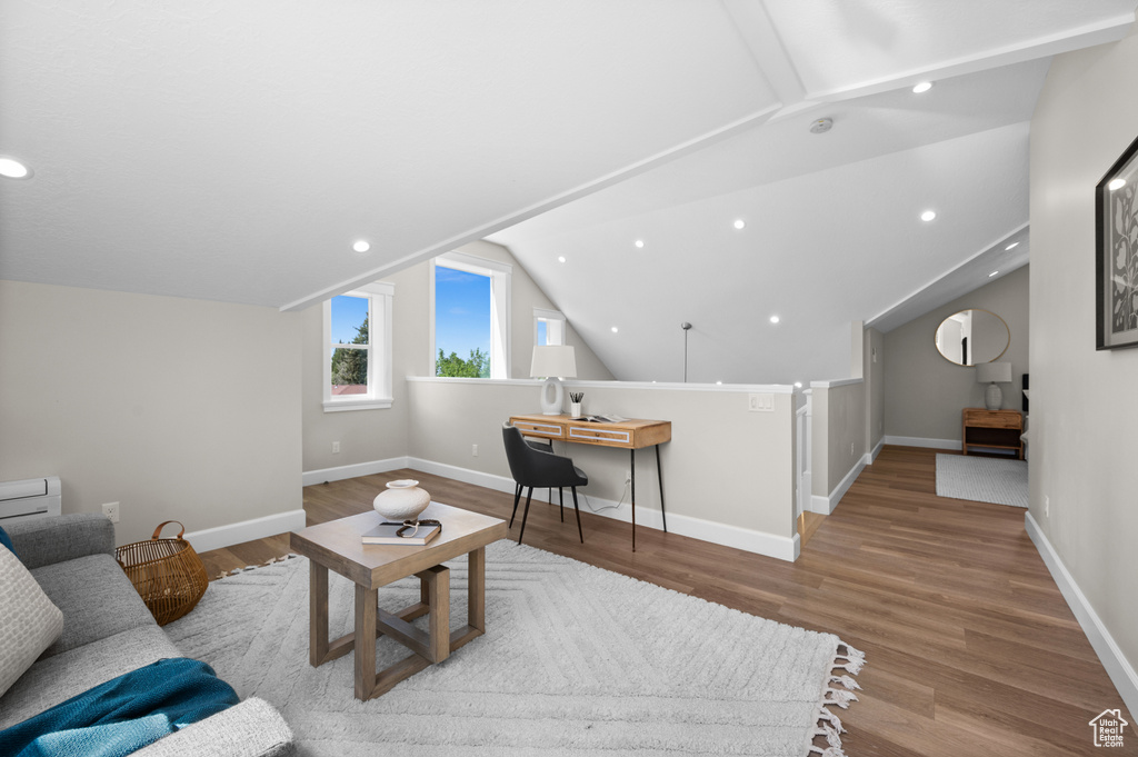 Living area featuring lofted ceiling, wood finished floors, baseboards, and recessed lighting