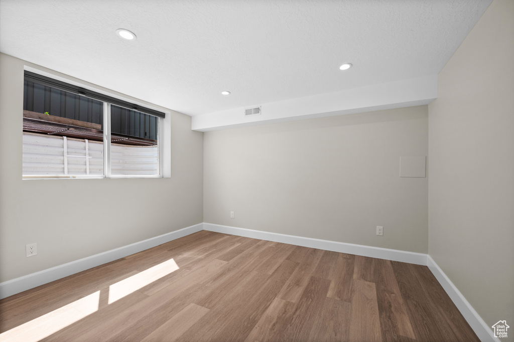 Spare room with wood finished floors, baseboards, and recessed lighting